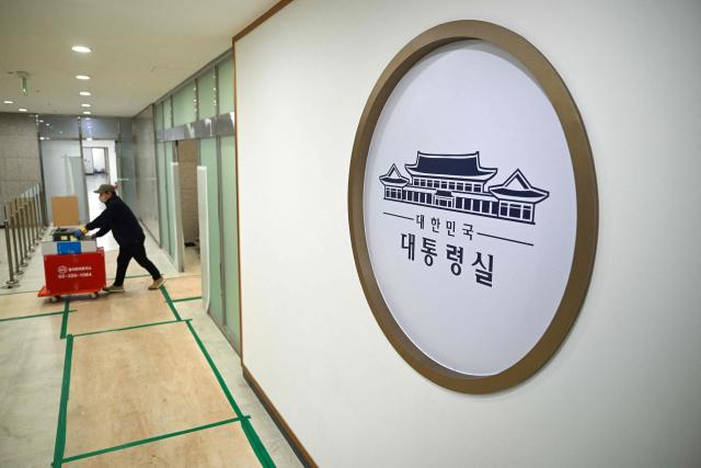 A worker carries boxes at the Presidential Office in Seoul on December 22, 2025, as South Korea's presidential office is moved back to the Blue House. South Korea's president and his team have started moving back into Seoul's historic Blue House and the process will be wrapped up by Christmas, an official said on December 9. (Photo by Jung Yeon-je / AFP)