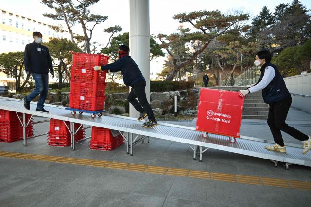 Workers carry boxes at the Presidential Office in Seoul on December 22, 2025, as South Korea's presidential office is moved back to the Blue House. South Korea's president and his team have started moving back into Seoul's historic Blue House and the process will be wrapped up by Christmas, an official said on December 9. (Photo by Jung Yeon-je / AFP)