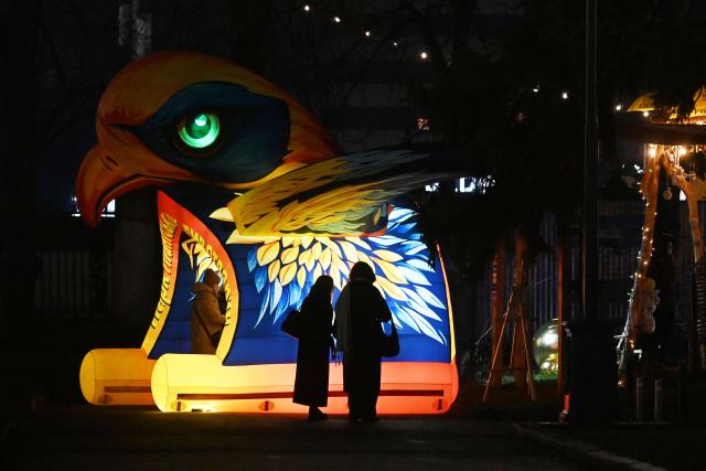 Visitors walk past a decoration at a Christmas Fair at the Ukrainian National Exhibition Center in Kyiv on December 21, 2025, amid the Russian invasion in Ukraine. (Photo by Sergei SUPINSKY / AFP)