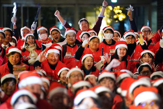 Office workers dressed as Santa Claus in Tokyo's Marunouchi business district participate in "Christmas Mission 2025," an event to liven up the area during the festive season, on December 22, 2025. (Photo by Kazuhiro NOGI / AFP)