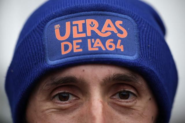 A farmer wears a beanie reading "The A64 ultras" during a farmers blockade to protest against the government's mandatory culling protocol for cattle herds affected by lumpy skin disease (dermatose nodulaire contagieuse), in Carbonne, south-western France on December 22, 2025. (Photo by Valentine CHAPUIS / AFP)