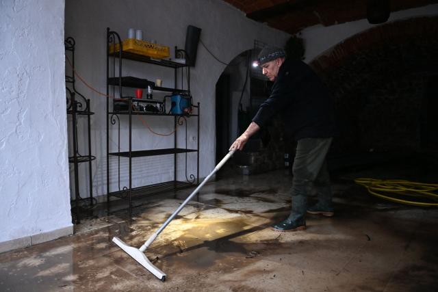 A man cleans up water inside a restaurant after the Herault river flooded following heavy rains in Laroque, southern France, on December 22, 2025. From Tarn to Var, five departments in the south of the country have been placed on orange alert on December 22, 2025 by Meteo-France for flooding or heavy rain. Aveyron and Tarn are also on orange alert for snow and ice. (Photo by Sylvain THOMAS / AFP)