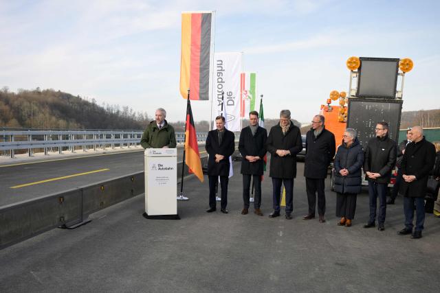 Luedenscheid's Mayor Sebastian Wagemeyer (L) speaks at the opening ceremony for the reconstructed Rahmede bridge with (L-R) Michael Guentner, CEO of the Motorway company, North-Rhine Westphalia's State Premier Hendrik Wuest, German Transport Minister Patrick Schnieder and German Chancellor Friedrich Merz on the A45 motorway, near Luedenscheid, western Germany on December 22, 2025. Following a routine inspection of the Rahmede viaduct in December 2021, inspectors discovered deformations in the steel wall that could affect the bridge's load-bearing capacity, leading to its reconstruction. (Photo by Sascha Schuermann / AFP)