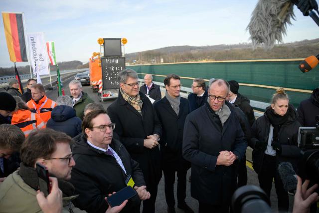 German Chancellor Friedrich Merz (R) speaks to journalists at the opening ceremony for the reconstructed Rahmede bridge on the A45 motorway, near Luedenscheid, western Germany on December 22, 2025. Following a routine inspection of the Rahmede viaduct in December 2021, inspectors discovered deformations in the steel wall that could affect the bridge's load-bearing capacity, leading to its reconstruction. (Photo by Sascha Schuermann / AFP)