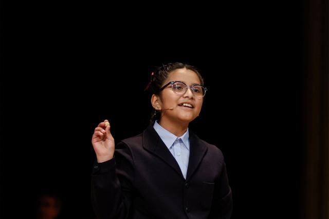 A schoolgirl shows the winning prize of Spain's Christmas lottery "El Gordo" (the Fat One) at the Royal Theatre in Madrid on December 22, 2025. (Photo by OSCAR DEL POZO / AFP)