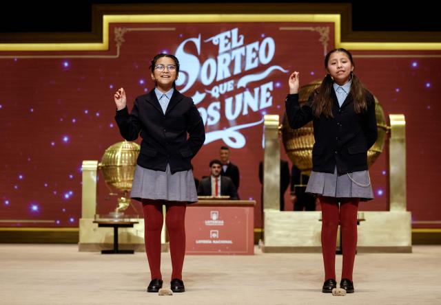 Schoolgirls show the winning prize of Spain's Christmas lottery "El Gordo" (the Fat One) at the Royal Theatre in Madrid on December 22, 2025. (Photo by OSCAR DEL POZO / AFP)