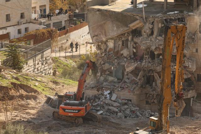 Excavators demolish a building constructed without a permit in the Wadi Qaddum area near the Silwan neighbourhood of east Jerusalem on December 22, 2025. Israeli bulldozers tore through a four-storey residential building in east Jerusalem on December 22, displacing scores of Palestinians in what activists said was the largest such demolition in the area this year. (Photo by AHMAD GHARABLI / AFP)