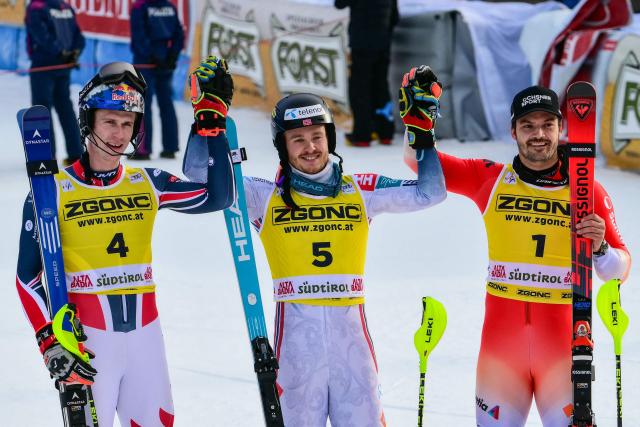 Second placed France's Clement Noel (L), first placed Norway's Atle Lie Mcgrath, and third placed Switzerland's Loic Meillard celebrate at the end of the second run of the Men's Slalom event, part of the FIS Alpine Ski World Cup 2025-2026, in Alta Badia, northern Italy, on December 22, 2025. (Photo by Stefano RELLANDINI / AFP)