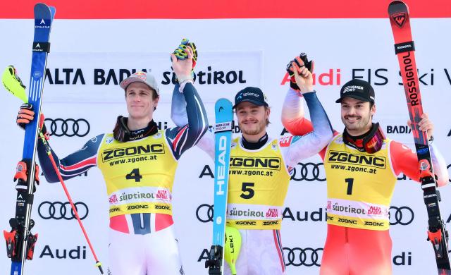 Second placed France's Clement Noel (L), First placed Norway's Atle Lie Mcgrath and third placed Switzerland's Loic Meillard celebrate on the podium of the Men's Slalom event, as part of the FIS Alpine Ski World Cup 2025-2026, in Alta Badia, northern Italy, on December 22, 2025. (Photo by Stefano RELLANDINI / AFP)