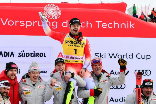 Third placed Switzerland's Loic Meillard (C) celebrates with teammates on the podium of the Men's Slalom event, as part of the FIS Alpine Ski World Cup 2025-2026, in Alta Badia, northern Italy, on December 22, 2025. (Photo by Stefano RELLANDINI / AFP)