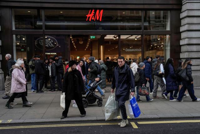 Shoppers walk past popular retail stores along a busy street in central London on December 22, 2025, as people try to do their last minute shopping for the Christmas and Boxing Day holidays. (Photo by CARLOS JASSO / AFP)