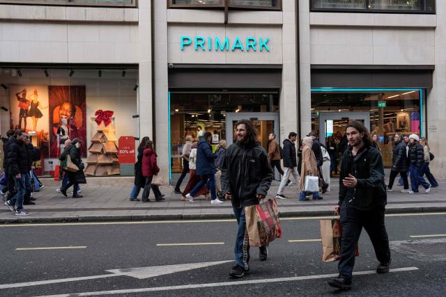 Shoppers walk past popular retail stores along a busy street in central London on December 22, 2025, as people try to do their last minute shopping for the Christmas and Boxing Day holidays. (Photo by CARLOS JASSO / AFP)