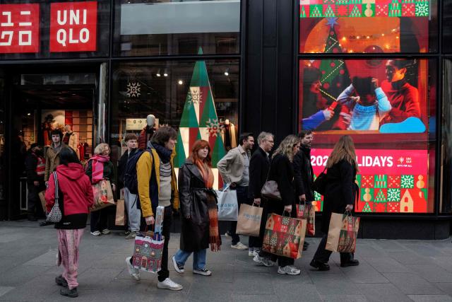 Shoppers walk past popular retail stores along a busy street in central London on December 22, 2025, as people try to do their last minute shopping for the Christmas and Boxing Day holidays. (Photo by CARLOS JASSO / AFP)
