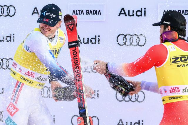 First placed Norway's Atle Lie Mcgrath (L) and third placed Switzerland's Loic Meillard celebrate by spraying sparkling wine on the podium of the Men's Slalom event, as part of the FIS Alpine Ski World Cup 2025-2026, in Alta Badia, northern Italy, on December 22, 2025. (Photo by Stefano RELLANDINI / AFP)