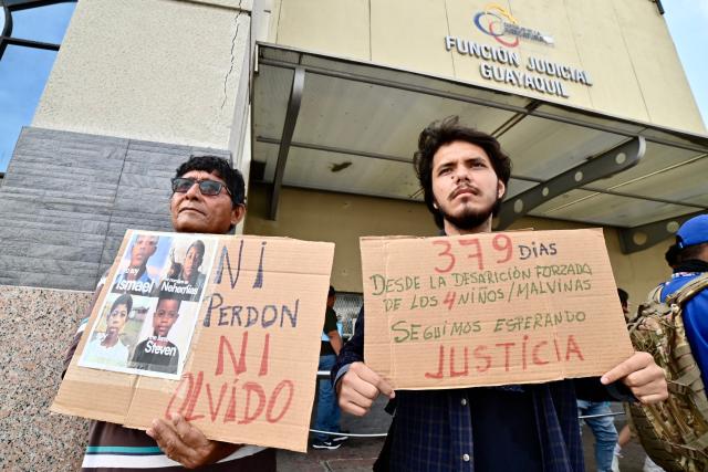 Relatives and members of Human Rights organizations hold signs reading "Neither forgiveness nor forgetting" and "379 days since the forced disappearance of the four children. We keep waiting for justice", outside a court in Guayaquil, Ecduador, on December 22, 2025, during a hearing of the militarymen involved in the case. Eleven Ecuadorian soldiers were sentenced to nearly 35 years in prison each for the forced disappearance of four minors, whose bodies were later found burned in 2024, the Attorney General's Office reported on Monday. (Photo by MARCOS PIN / AFP)