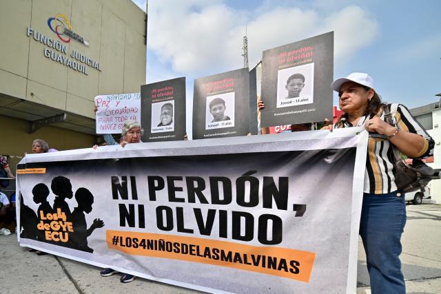Relatives and members of Human Rights organizations hold pictures and a banner reading "Neither forgiveness nor forgetting", outside a court in Guayaquil, Ecduador, on December 22, 2025, during a hearing of the militarymen involved in the case of the forced disapperance of four children. Eleven Ecuadorian soldiers were sentenced to nearly 35 years in prison each for the forced disappearance of four minors, whose bodies were later found burned in 2024, the Attorney General's Office reported on Monday. (Photo by MARCOS PIN / AFP)