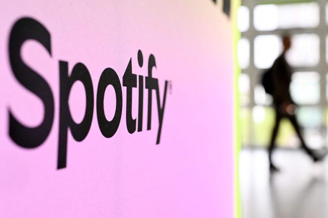(FILES) A person walks past a banner with a Spotify logo at the Frankfurt book fair on October 17, 2024, on the second day of the world's biggest book fair in Frankfurt am Main, western Germany. Music streaming service Spotify said on December 22, 2025 it had disabled accounts from a piracy activist hacker group that claimed to have "backed up" millions of Spotify's music files and metadata. The group Anna's Archives said in a blog post it had backed up 86 million Spotify tracks and the metadata for 256 million tracks -- a process known as "scraping" -- in order to start an open "preservation archive" for music. (Photo by Kirill KUDRYAVTSEV / AFP)