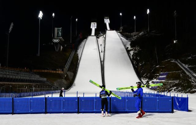 Athletes carry their ski as they take part in a training session at the Ski Jumping arena prior the Open Italian Championship of ski jumping in Predazzo, on December 22, 2025. The Ski Jumping arena in Predazzo will host the ski jumping and nordic combined competitions, during the Milano Cortina 2026 Winter Olympic Games. (Photo by Stefano RELLANDINI / AFP)
