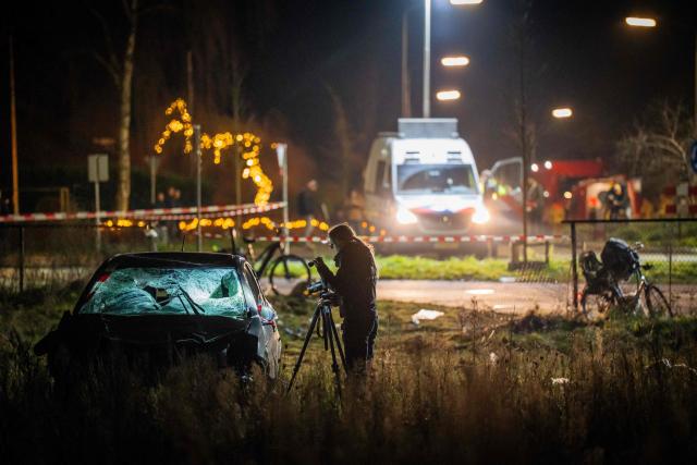 TOPSHOT - A forensics officer takes photographs of a car at the scene of a serious accident where a car drove through a crowd during a parade in Nunspeet on December 22, 2025. Nine people were hurt, three seriously, in the incident with police saying they did not initially suspect an attack. (Photo by Roland HEITINK / ANP / AFP) / Netherlands OUT