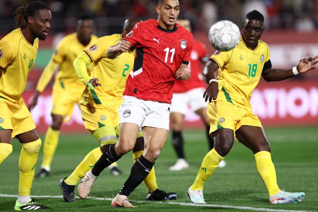 Guest, Egypt's forward #11 Mostafa Mohamed (L) and Zimbabwe's midfielder #18 Marvelous Nakamba compete for the ball during the Africa Cup of Nations (CAN) group B football match between Egypt and Zimbabwe at Adrar Stadium in Agadir on December 22, 2025. (Photo by FRANCK FIFE / AFP)