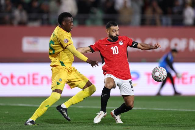 Zimbabwe's defender #15 Teenage Hadebe challenges as Egypt's forward #10 Mohamed Salah goes on to score the second goal during the Africa Cup of Nations (CAN) group B football match between Egypt and Zimbabwe at Adrar Stadium in Agadir on December 22, 2025. (Photo by FRANCK FIFE / AFP)