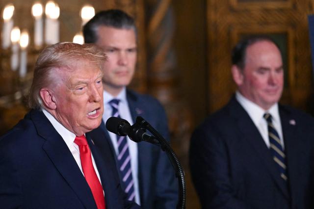 US President Donald Trump (L) flanked by US Secretary of Defense Pete Hegseth (C) and US Navy Secretary John Phelan (R), announces the US Navy’s new Golden Fleet initiative, unveiling a new class of frigates, at Mar-a-Lago in Palm Beach, Florida, on December 22, 2025. (Photo by ANDREW CABALLERO-REYNOLDS / AFP)