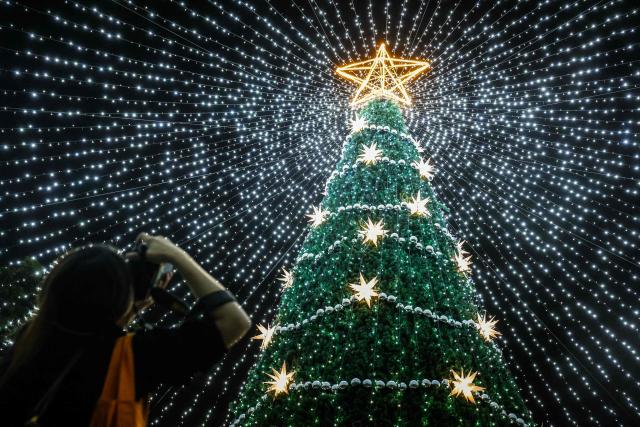 A woman take photos of Christmas decorations during the Pingtung Christmas Festival in Pingtung on December 22, 2025. (Photo by I-Hwa Cheng / AFP)