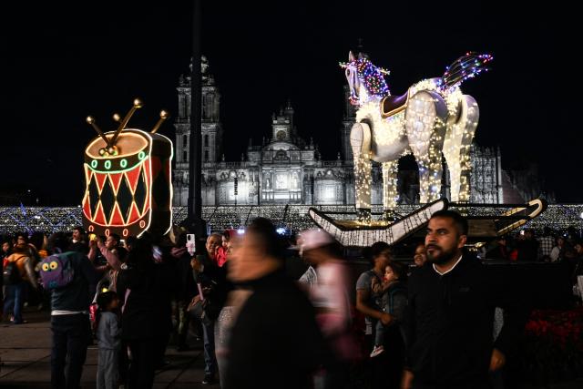 People attend a Christmas light festival at the Zocalo square in Mexico City on December 22, 2025. (Photo by Yuri CORTEZ / AFP)