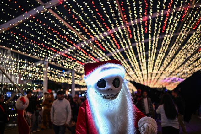 A person dressed as Jack Skellington, the character from the film "The Nightmare Before Christmas", stands during a Christmas light festival at the Zocalo square in Mexico City on December 22, 2025. (Photo by Yuri CORTEZ / AFP)