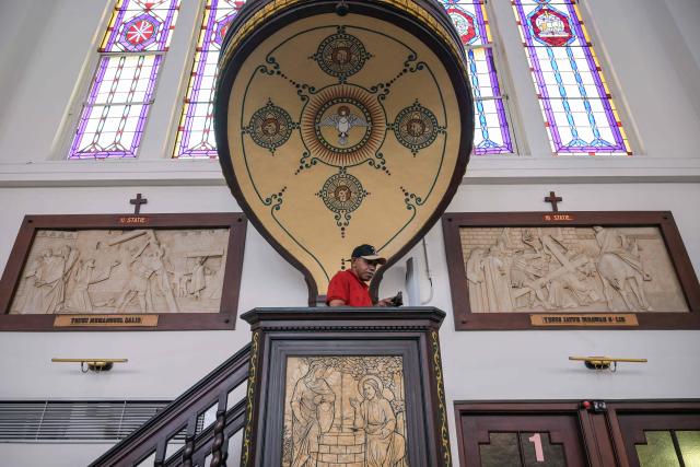 A worker cleans a pulpit at the Sacred Heart of Jesus Cathedral, known locally as the "Hati Kudus Yesus" church, during preparations for Christmas Mass in Surabaya, Indonesia's East Java province on December 23, 2025. (Photo by JUNI KRISWANTO / AFP)