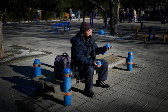 A man juggles spikey balls at a park in Beijing on December 23, 2025. (Photo by WANG Zhao / AFP)