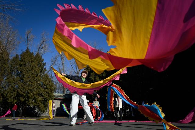 People dance with ribbons at a park in Beijing on December 23, 2025. (Photo by WANG Zhao / AFP)
