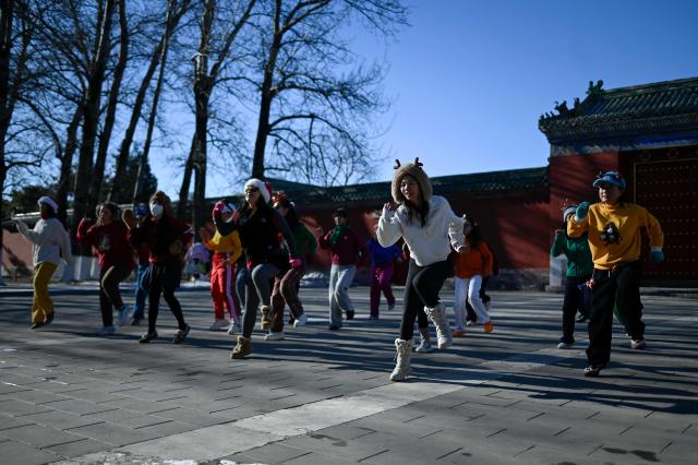 A group of women dance at a park in Beijing on December 23, 2025. (Photo by WANG Zhao / AFP)