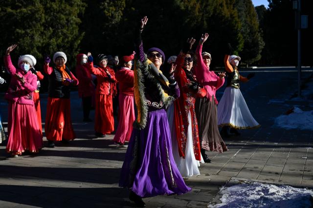 A group of women dance at a park in Beijing on December 23, 2025. (Photo by WANG Zhao / AFP)