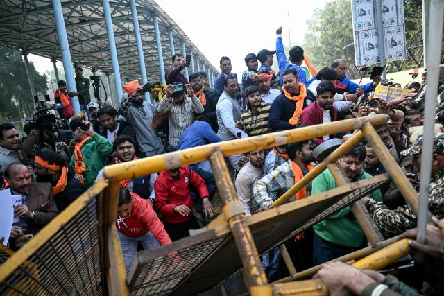 Vishva Hindu Parishad (VHP) activists along with others topple a barricade during a protest near the Bangladesh High Commission in New Delhi on December 23, 2025, to condemn the lynching of Hindu garment worker Dipu Chandra Das. (Photo by Arun SANKAR / AFP)