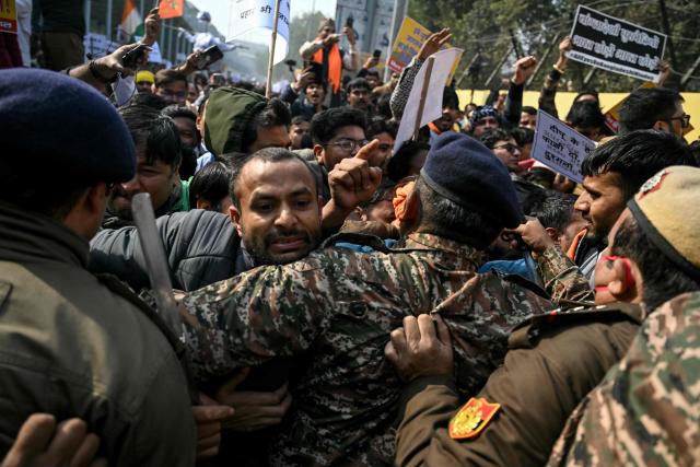 Security personnel try to stop Vishva Hindu Parishad (VHP) activists along with others during a protest march near the Bangladesh High Commission in New Delhi on December 23, 2025, to condemn the lynching of Hindu garment worker Dipu Chandra Das. (Photo by Arun SANKAR / AFP)