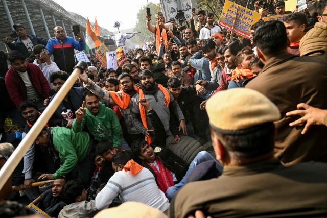 Security personnel try to stop Vishva Hindu Parishad (VHP) activists along with others during a protest march near the Bangladesh High Commission in New Delhi on December 23, 2025, to condemn the lynching of Hindu garment worker Dipu Chandra Das. (Photo by Arun SANKAR / AFP)