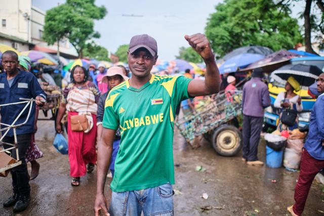 Israel Makusha, gestures while wearing a Zimbabwe national soccer team shirt gestures at a market in Bulawayo, Zimbabwe, on December 22, 2025. Zimbabweans briefly gathered in a shared football moment, coinciding with the 1987 accord after the Gukurahundi massacres, which killed about 20,000 minority Ndebele. (Photo by Zinyange Auntony / AFP)