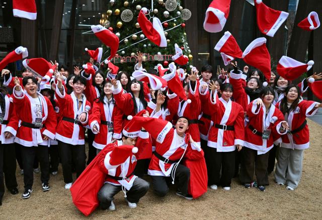 South Korean volunteers dressed as Santa Claus throw Santa hats during a ceremony before the delivery of Christmas gifts for the underprivileged at Songpa District Office in Seoul on December 23, 2025. (Photo by Jung Yeon-je / AFP)