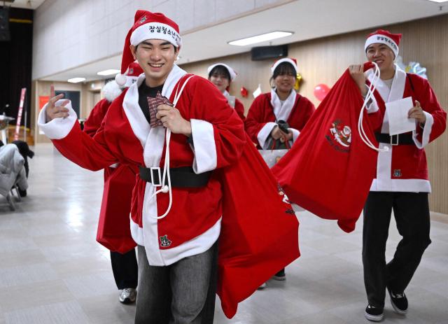 South Korean volunteers dressed as Santa Claus carry Christmas gift packages to deliver them to the underprivileged at Songpa District Office in Seoul on December 23, 2025. (Photo by Jung Yeon-je / AFP)