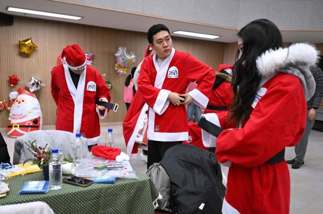 South Korean volunteers wear Santa Claus outfits during a ceremony before the delivery of Christmas gifts for the underprivileged at Songpa District Office in Seoul on December 23, 2025. (Photo by Jung Yeon-je / AFP)