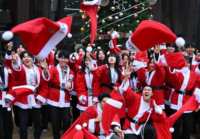 South Korean volunteers dressed as Santa Claus throw Santa hats during a ceremony before the delivery of Christmas gifts for the underprivileged at Songpa District Office in Seoul on December 23, 2025. (Photo by Jung Yeon-je / AFP)