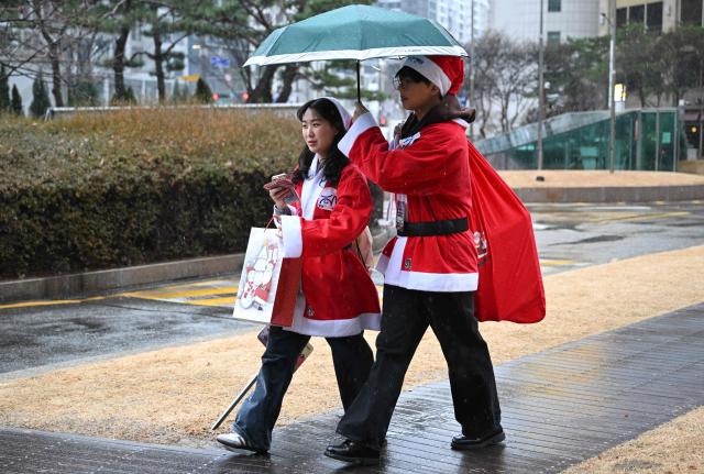South Korean volunteers dressed as Santa Claus carry Christmas gift packages to deliver them to the underprivileged at Songpa District Office in Seoul on December 23, 2025. (Photo by Jung Yeon-je / AFP)