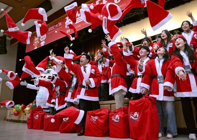 South Korean volunteers dressed as Santa Claus throw Santa hats during a ceremony before the delivery of Christmas gifts for the underprivileged at Songpa District Office in Seoul on December 23, 2025. (Photo by Jung Yeon-je / AFP)