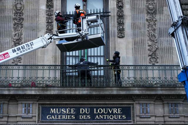 Workers install iron window guards on the window of the Gallerie d'Apollon (Apollo's gallery) of the Louvre Museum, on the Quai Francois Mitterrand side, in Paris on December 23, 2025 a few weeks after thieves used a furniture lift to break into the museum. Robbers broke into the Louvre and fled with jewellery on October 19, 2025 morning after arriving on a scooter armed with small chainsaws and used a goods lift to reach the room they were targeting. (Photo by Dimitar DILKOFF / AFP)