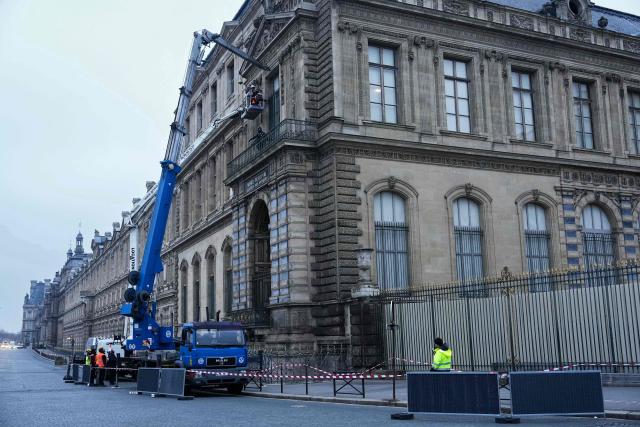 Workers install iron window guards on the window of the Gallerie d'Apollon (Apollo's gallery) of the Louvre Museum, on the Quai Francois Mitterrand side, in Paris on December 23, 2025 a few weeks after thieves used a furniture lift to break into the museum. Robbers broke into the Louvre and fled with jewellery on October 19, 2025 morning after arriving on a scooter armed with small chainsaws and used a goods lift to reach the room they were targeting. (Photo by Dimitar DILKOFF / AFP)