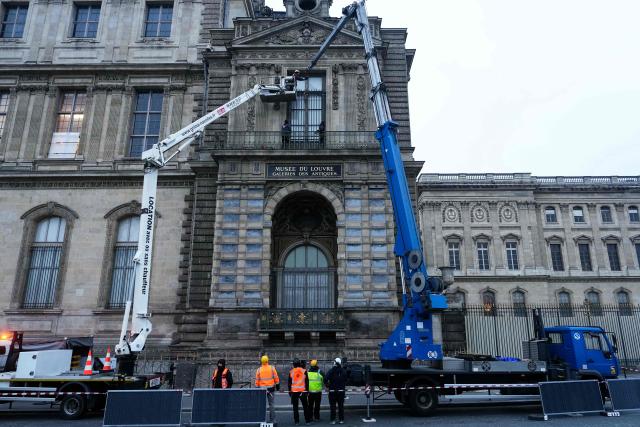 Workers install iron window guards on the window of the Gallerie d'Apollon (Apollo's gallery) of the Louvre Museum, on the Quai Francois Mitterrand side, in Paris on December 23, 2025 a few weeks after thieves used a furniture lift to break into the museum. Robbers broke into the Louvre and fled with jewellery on October 19, 2025 morning after arriving on a scooter armed with small chainsaws and used a goods lift to reach the room they were targeting. (Photo by Dimitar DILKOFF / AFP)
