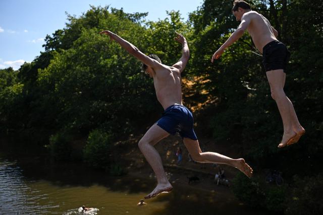 (FILES) Teenagers cool off by leaping from the Wey footbridge into the River Wey, near Guildford, south of London on July 13, 2025, as the heatwave in England continues. 2025 may have been Britain's hottest on record, with an average temperature above 10 degrees Celsius, the national weather service said on December 23, 2025. Definitive figures for 2025 will be released on January 2, 2026 but as of the final week of this year, the average temperature has been 10.05C. The previous high was 10.03C in 2022, the Met Office said. (Photo by Justin TALLIS / AFP)