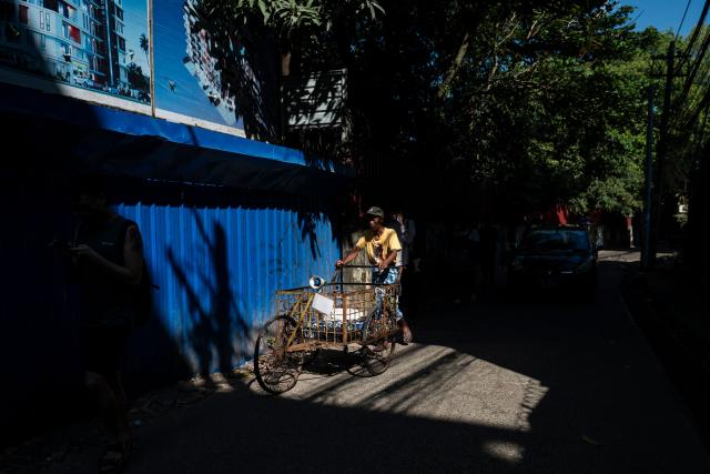 A man pushes a cart along a street in Yangon on December 23, 2025. (Photo by Sai Aung MAIN / AFP)