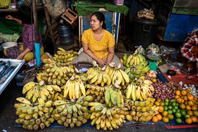 A banana and fruit vendor waits for customer at a street market in Yangon on December 23, 2025. (Photo by Sai Aung MAIN / AFP)